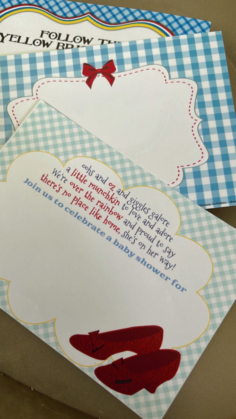 Colorful Wizard of Oz invitations decorated with ruby slippers, sparkling stars, yellow brick road accents, Emerald City graphics, and rainbow elements