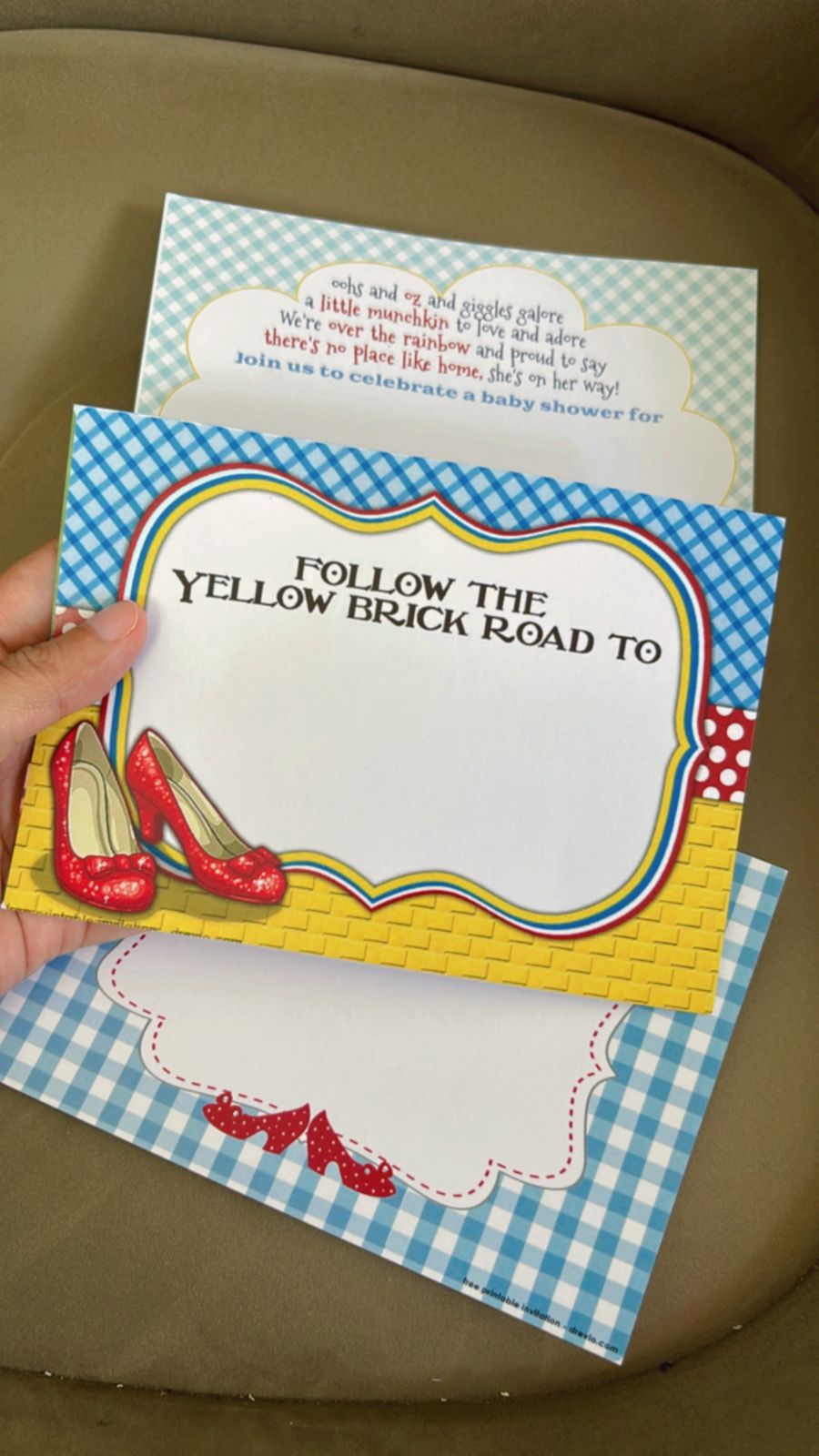 Wizard of Oz themed invitation design surrounded by ruby slippers, Emerald City towers, rainbow artwork, Toto illustrations, and golden road details