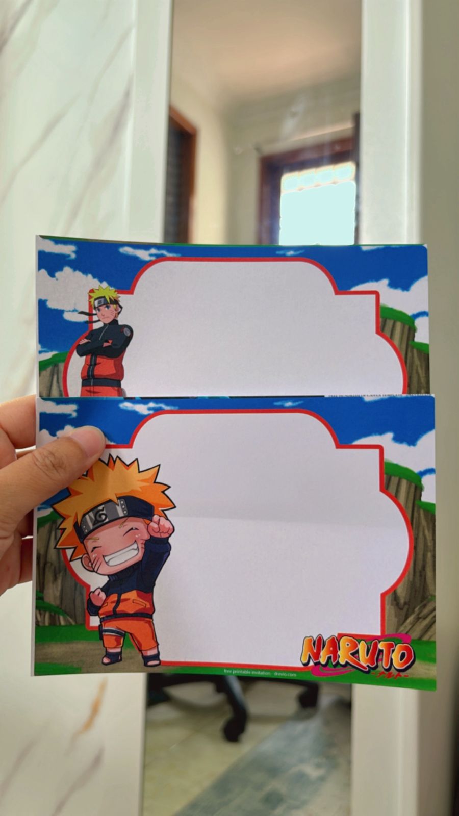 Flat lay of Naruto birthday invitation design with chakra swirl patterns, anime characters, and black-orange palette