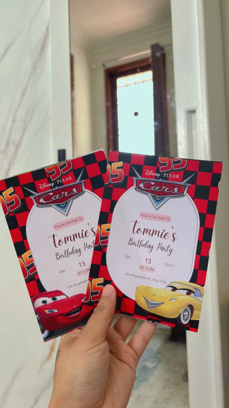 Cars-themed birthday invite with checkered flags, road signs, racing numbers, and Lightning McQueen party elements
