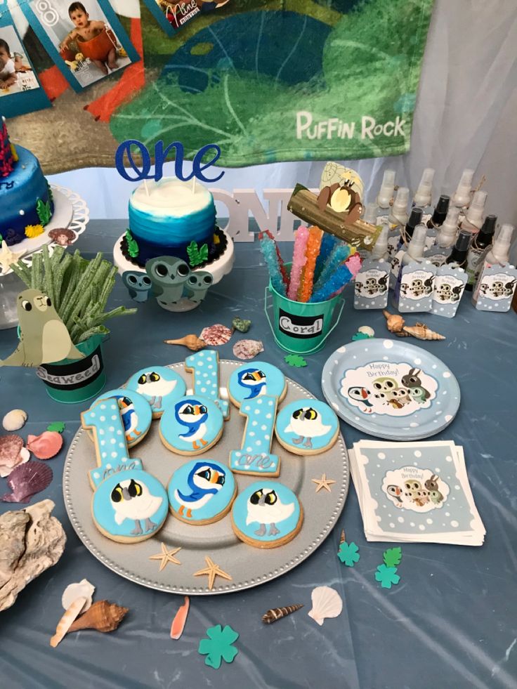 Watercolor Puffin Rock birthday invitation decorated with coastal island plants, pebbles, tiny puffins, butterflies, and wildflower elements