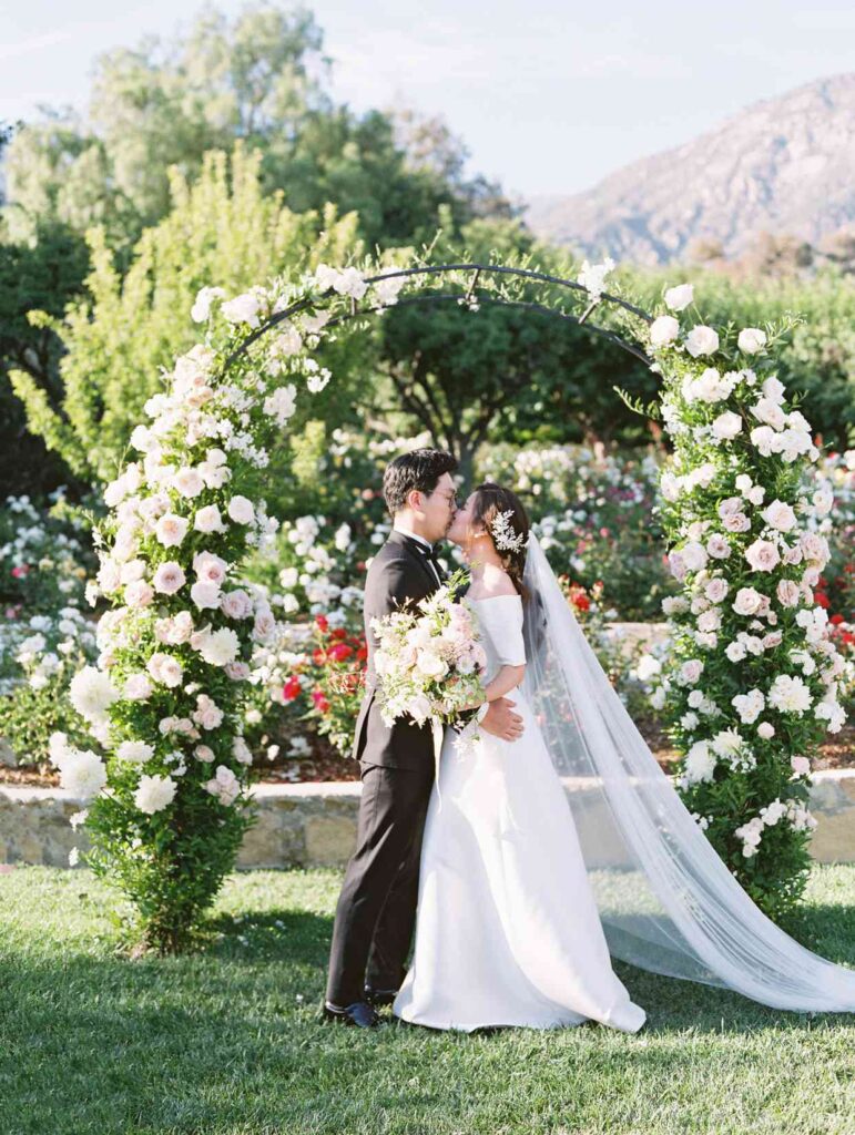 Beautiful Bride and Groom Pose for Photoshoot and standing in front of Flower Arch