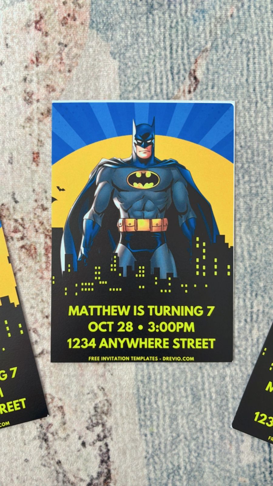Dark Gotham-themed invitation with foggy textures, spotlight beam, bat silhouette, and modern bold lettering