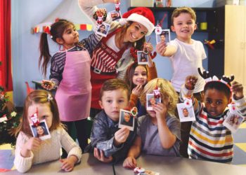 Preschool teacher taking instant print transfer to decorate a Christmas Tree, Quebec, Canada