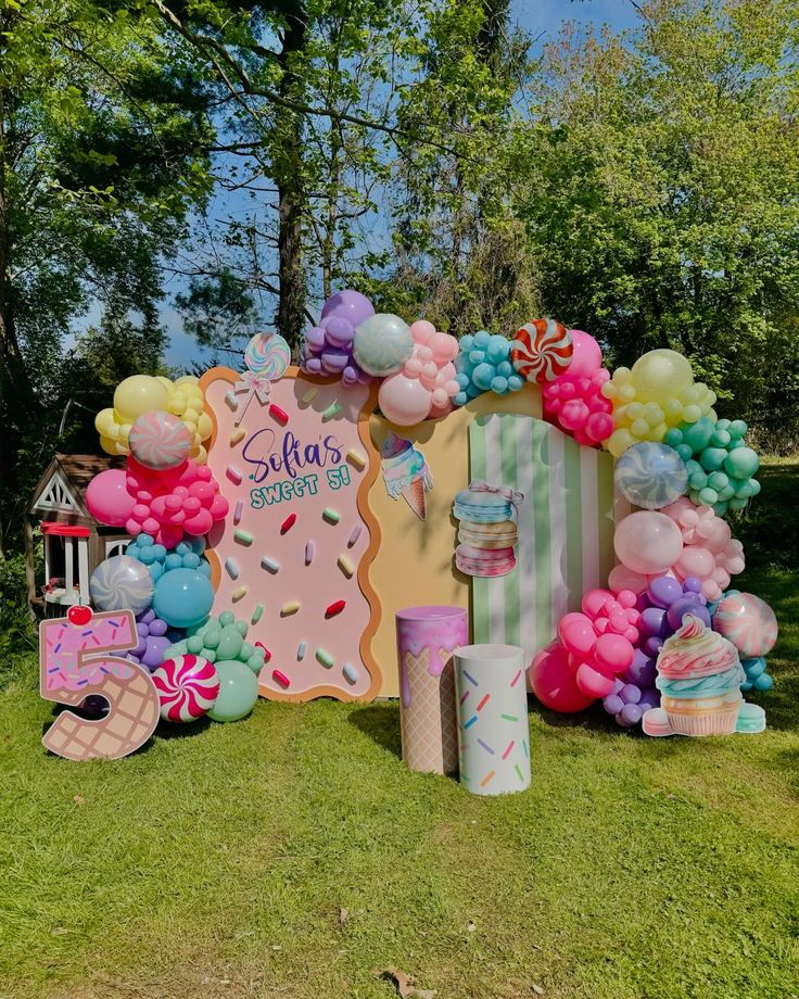 Free Candyland invitation design surrounded by giant lollipops, marshmallows, jelly beans, cupcakes, and colorful candy-inspired decorations.